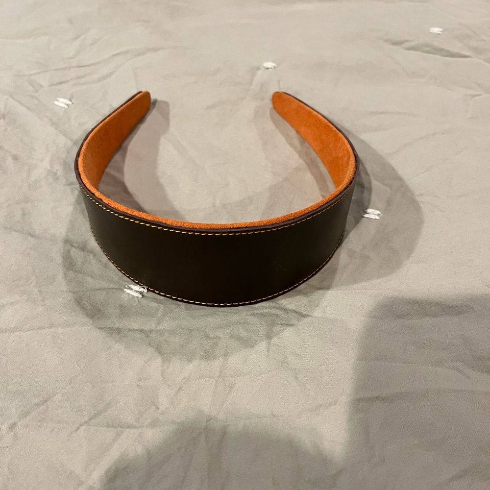 Brown leather headband with contrast orange stitching.